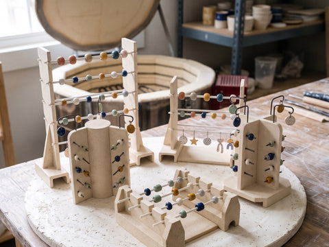 Handmade kiln bead racks and bead trees loaded with glazed beads on a kiln shelf, made from Clay Hole paper templates