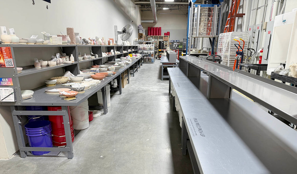 Long runs of drop-off and pickup tables holding finished and unfired pottery.