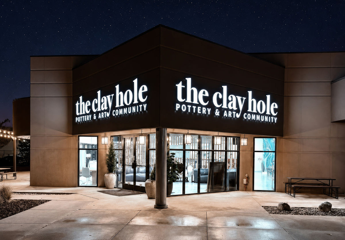 The Clay Hole at night: the lit storefront signage under a star-filled sky, with light reflecting off the wet concrete out front.