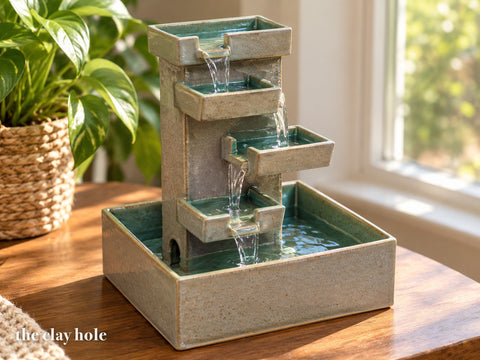 A stoneware tabletop cascade fountain made from The Clay Hole paper template, water spilling from tray to tray into its basin