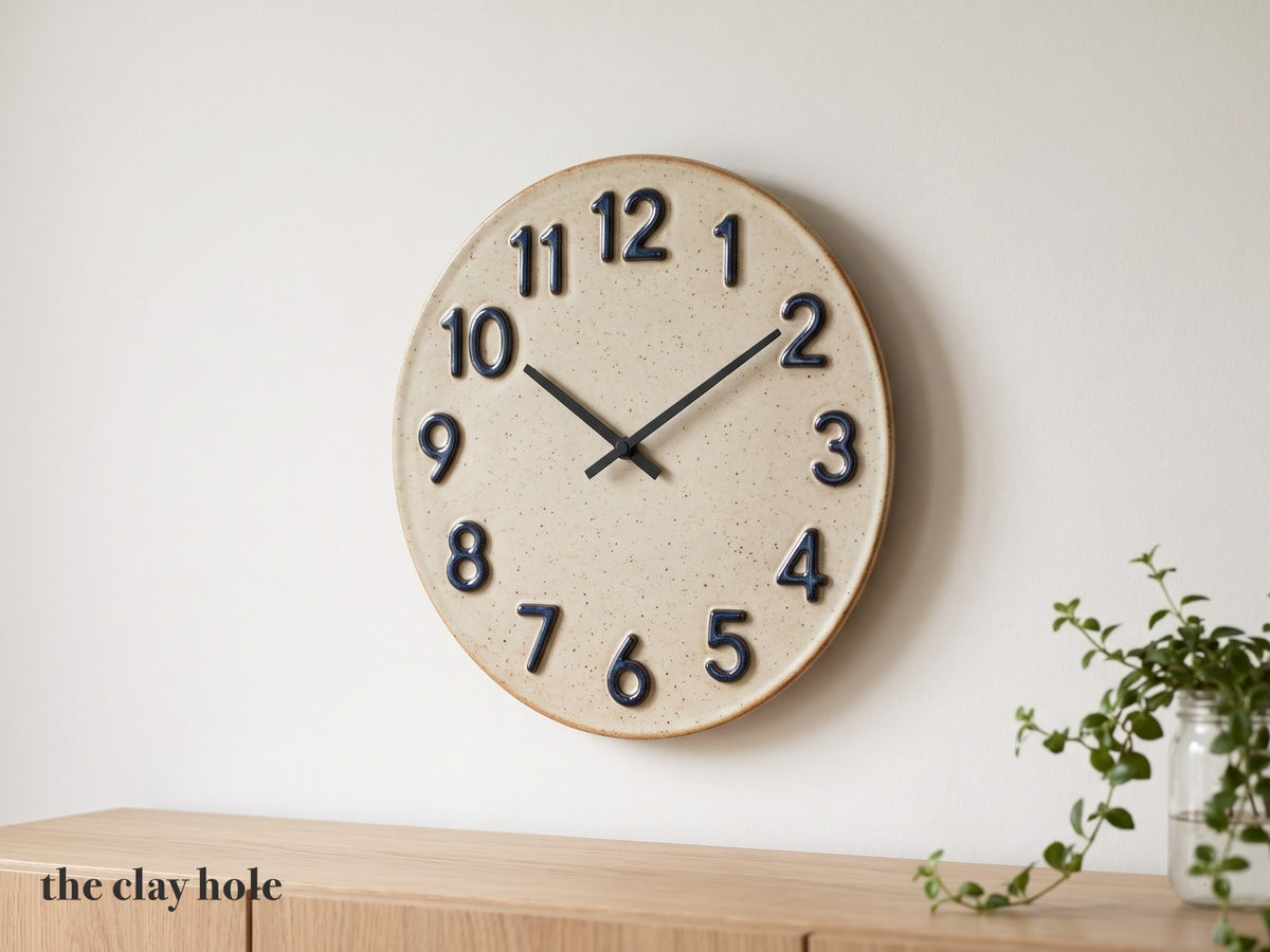 A handmade 14 inch stoneware wall clock with raised indigo numbers, made from The Clay Hole paper template