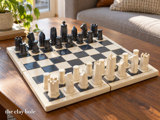 A stoneware chess set with six-sided pieces on a cream and charcoal board, made from The Clay Hole paper template