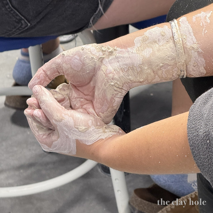 Hands coated in drying clay slip after a session on the pottery wheel