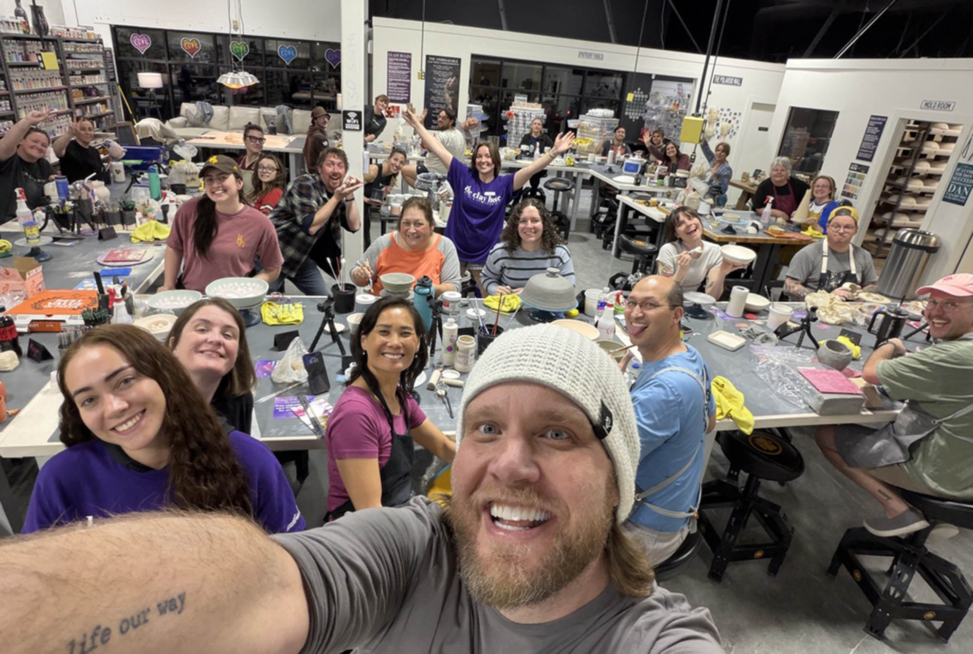 A full class at The Clay Hole crowded around the tables, laughing with their arms in the air