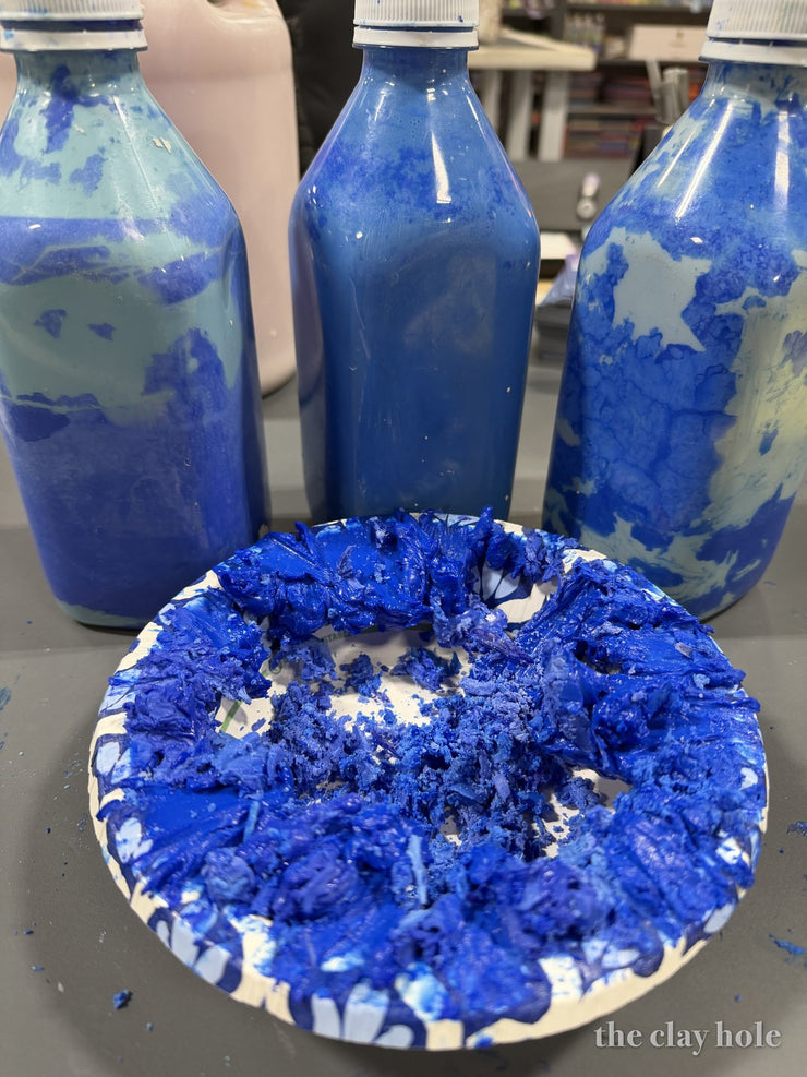 Close up of dried cobalt blue glaze flakes cracking and curling off a plate