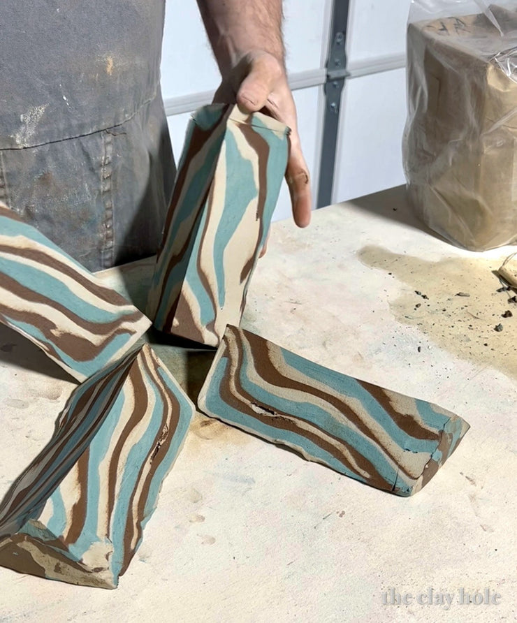 Cut blocks of marbled pottery clay showing blue, brown and cream agateware stripes