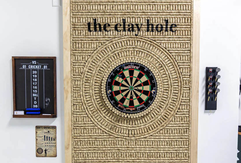 A dart board mounted on a studio wall with a throwing lane in front of it.