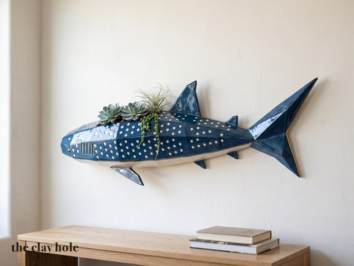 A faceted deep blue whale shark wall planter with white spots, made from The Clay Hole paper template, planted along its back