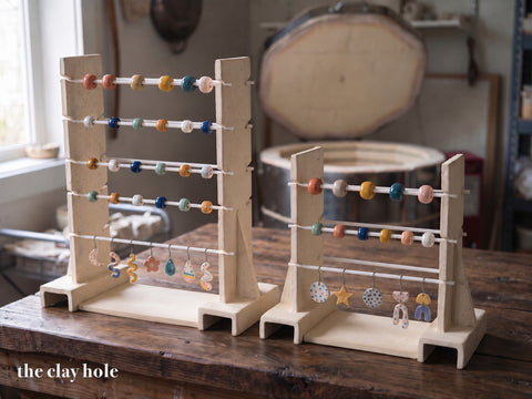 Two handmade stoneware kiln bead racks, a tall one and a small one, with glazed beads on white alumina rods, made from a Clay Hole paper template