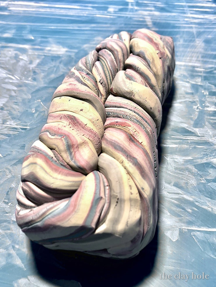 Twisted loaf of marbled agateware pottery clay in pink, gray and cream stripes