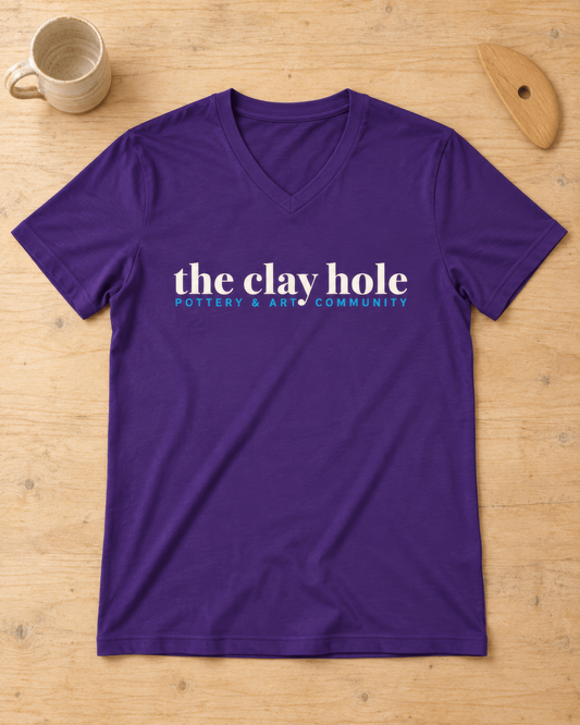 Purple The Clay Hole men's v-neck t-shirt laid flat on a wooden studio table