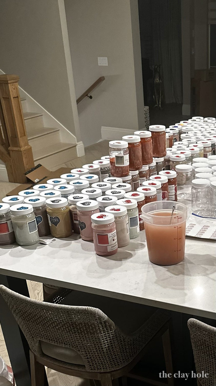 Dozens of small labeled jars of pottery glaze test batches covering a kitchen island