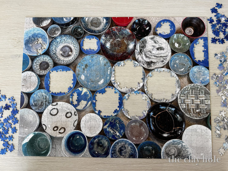 Half finished jigsaw puzzle picturing shelves of colorful pottery bowls
