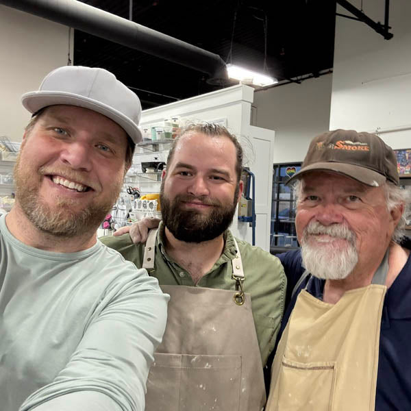 Three friends in aprons laughing together at The Clay Hole