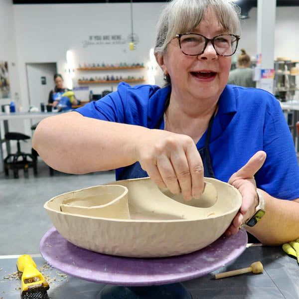 An older Clay Hole member smiling over a large hand-built bowl