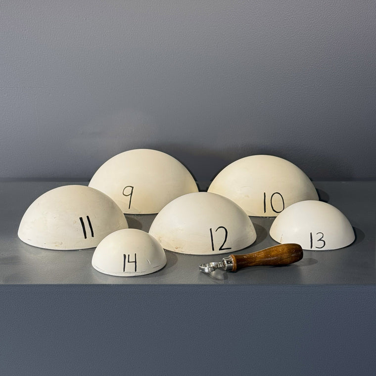 White pottery plaster hump mold number 9: a smooth half-sphere dome, one of a family of six graduated domes, shown rim-down on the gray shelf and hand-numbered 9.