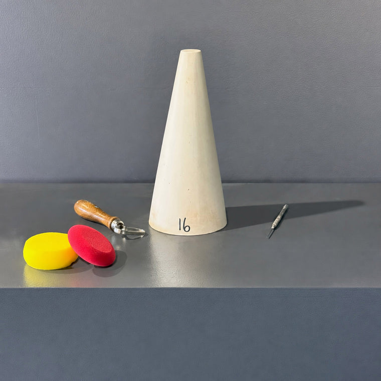 White pottery plaster mold number 16: a tall narrow cone, standing point-up on the gray shelf.