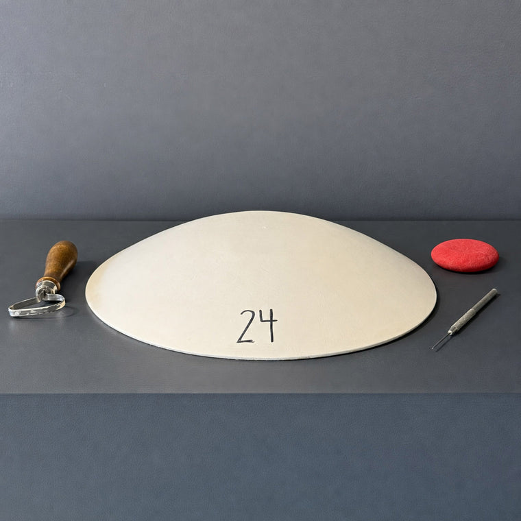 White pottery plaster hump mold number 24: an oval platter mold, rim-down on the gray shelf.