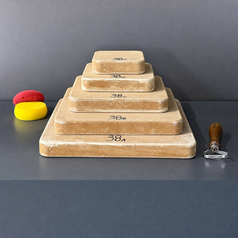 High-density fiberboard mold 38A: a thick rounded rectangular block, the largest of a 5-piece nesting set shown stacked largest to smallest on the gray shelf, hand-labeled 38A.