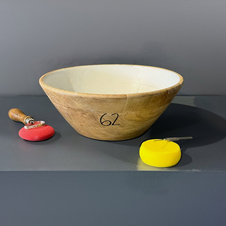 Turned wooden bowl used as mold number 62: a medium wooden bowl, measuring 12.2 in wide, 12.2 in deep and 5.3 in tall with a white painted interior, sitting upright on the gray shelf.