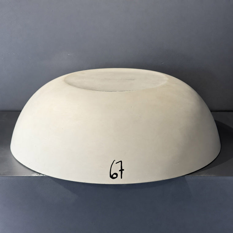 White pottery plaster hump mold number 67: a very large shallow dome, filling most of the frame on the gray shelf.