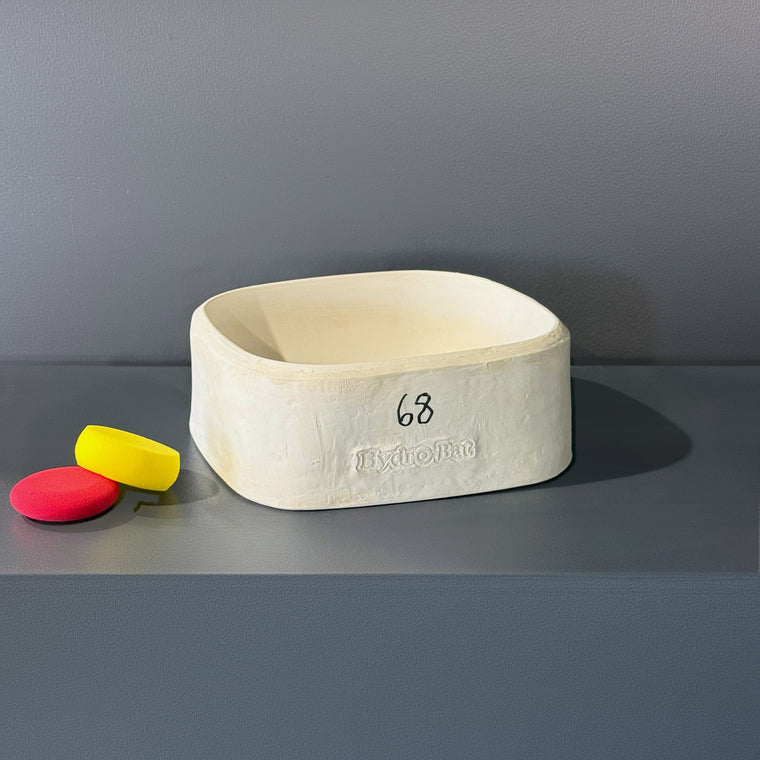 White plaster slump mold number 68: a rounded rectangular open box, embossed Hydro-Bat on the side, sitting cavity-up on the gray shelf.