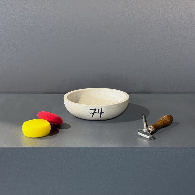 White stone bowl used as mold number 74: a small marble or stone bowl, sitting upright on the gray shelf.