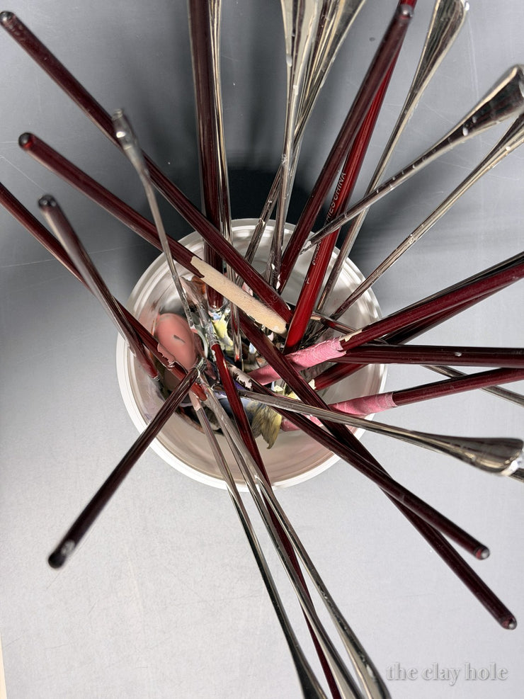 Red handled pottery trimming tools fanned out of a jar, photographed from above