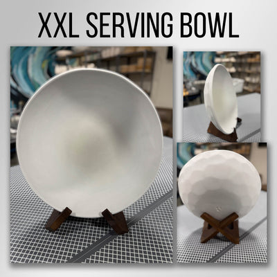 A large round bisque-fired stoneware serving bowl on a wooden stand in the studio