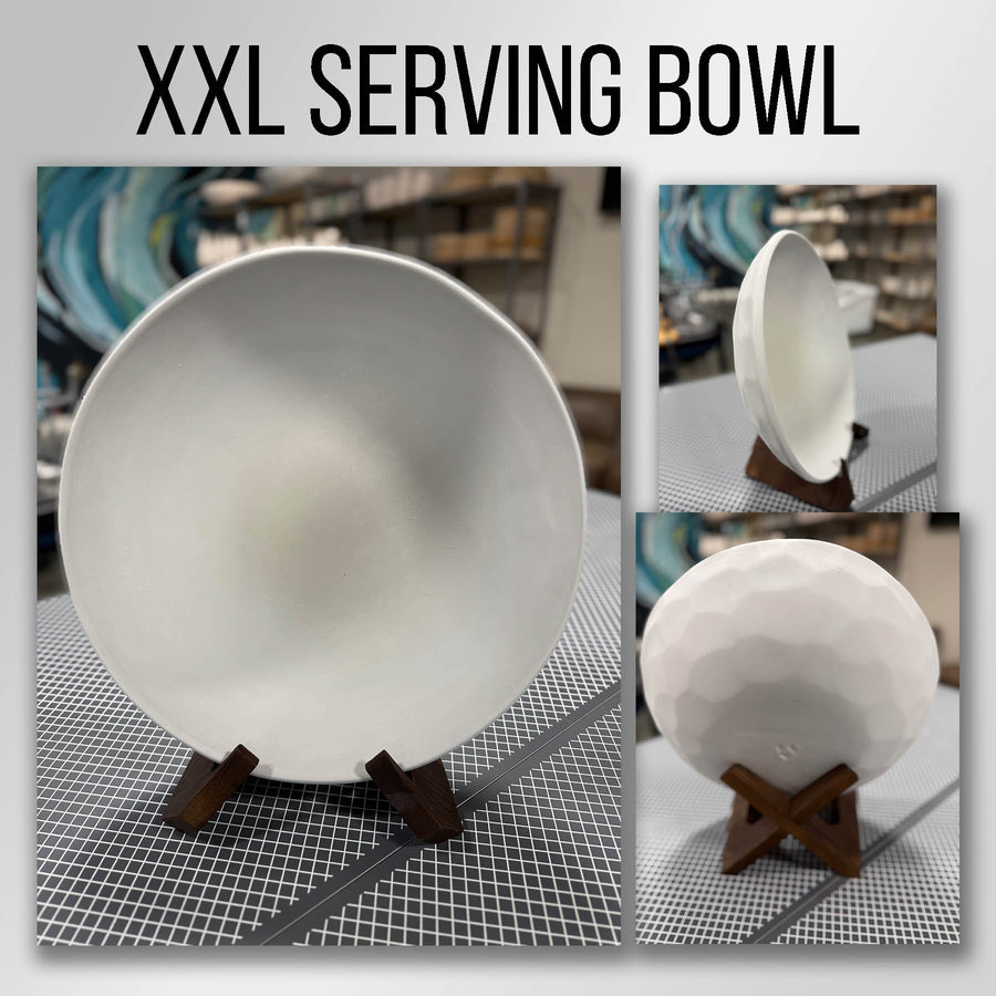 A large round bisque-fired stoneware serving bowl on a wooden stand in the studio