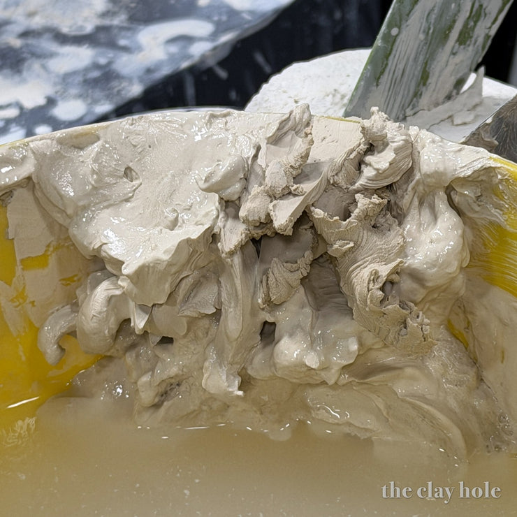 Dry pottery clay scraps slaking down into water in a studio reclaim bucket