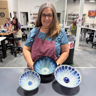 A member standing behind three bowls with blue and white petal patterns spreading out from a dark center at The Clay Hole pottery studio in Draper, Utah
