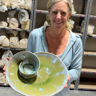 A member holding a wide yellow green platter with a small bowl attached in the center at The Clay Hole pottery studio in Draper, Utah