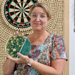 A member holding a round plate split between bubbled green and gold glaze and smooth teal at The Clay Hole pottery studio in Draper, Utah