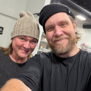 Two friends smiling in a selfie, one in a tan knit beanie and one in a black beanie at The Clay Hole in Draper, Utah