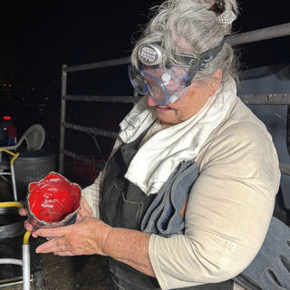 A person in goggles and a headlamp holds a small bowl with a glossy red center and dark gray rim at The Clay Hole in Draper, Utah