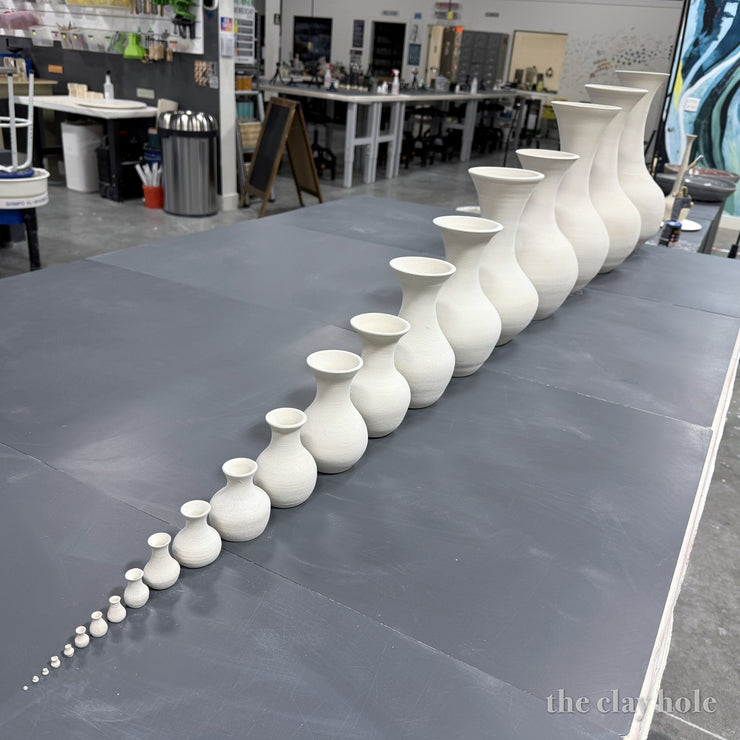 Wheel thrown vases lined up from tiny to tall across studio tables at The Clay Hole