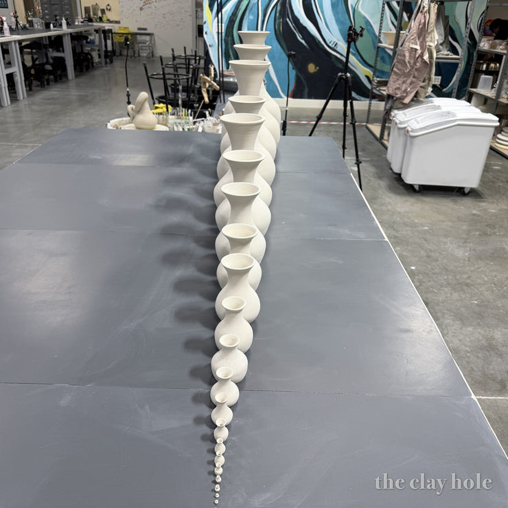 A straight line of thrown vases growing from thumb sized to full sized, viewed head on