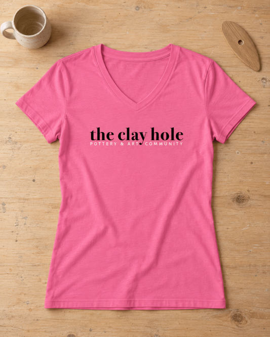 Pink The Clay Hole women's v-neck t-shirt laid flat on a wooden studio table