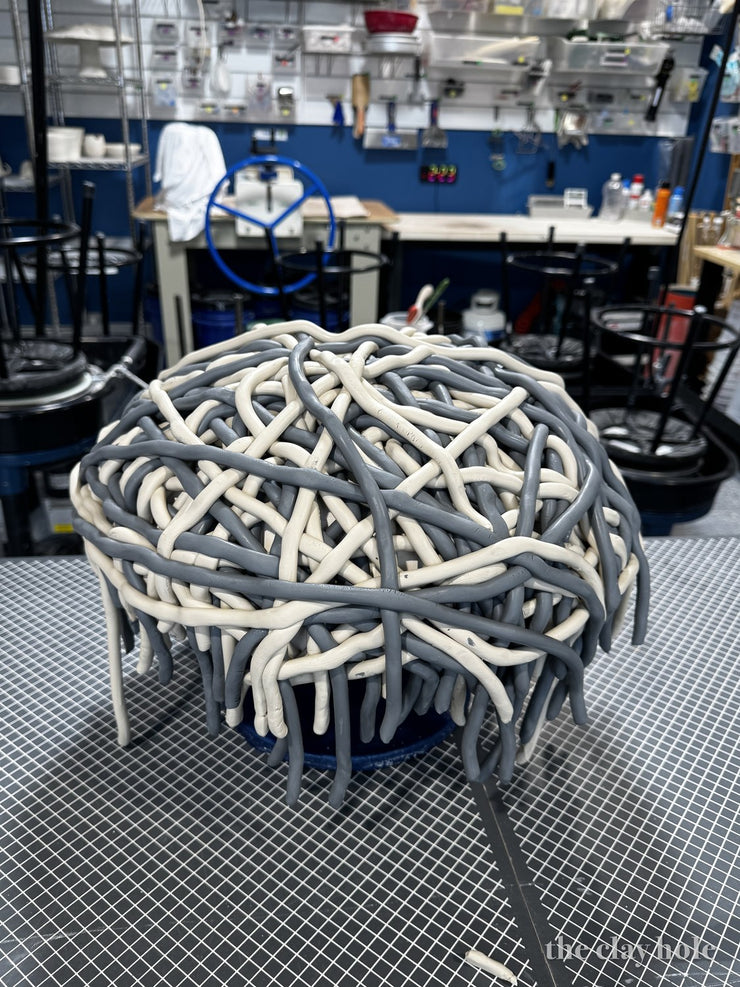 Gray and cream clay coils woven into a dome over a form to build a basket
